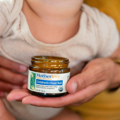 Mom holding baby and jar of Children's Chest Rub