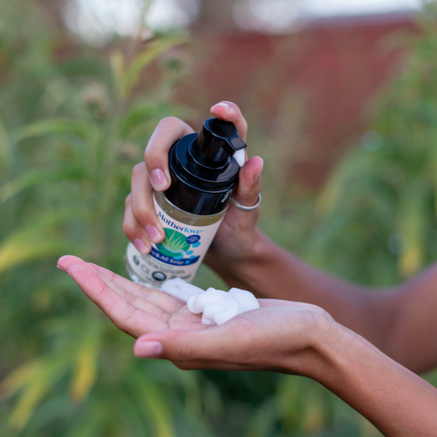 Foaming castile soap being pumped into hand with nature in background