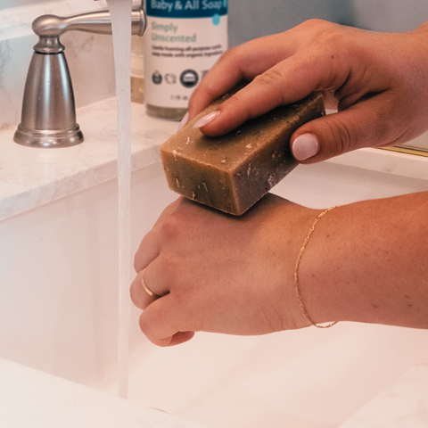 Person washing hands at sink with bar of soap