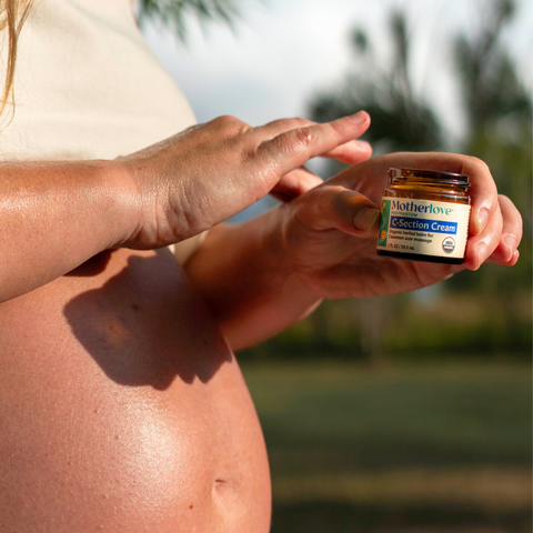 Person holding a jar of Motherlove C-Section Cream outdoors