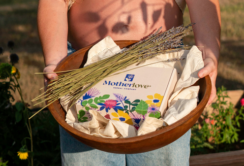 Person holding a bowl with Motherlove products in a garden setting