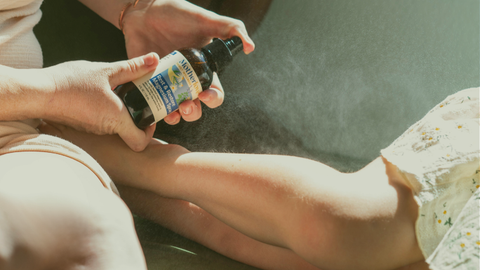 Person holding a bottle of magnesium spray over another person's leg with spray coming out of bottle.