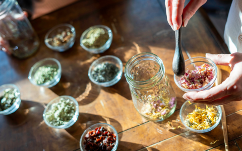 Person preparing ingredients in small glass containers on a wooden surface