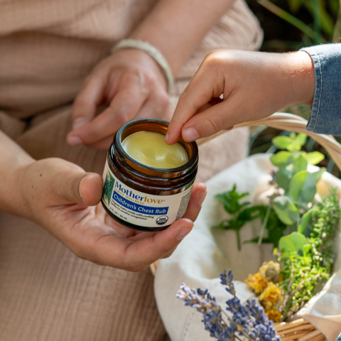 Jar of Children's Chest Rub held by a hand with a child sticking it's finger into it