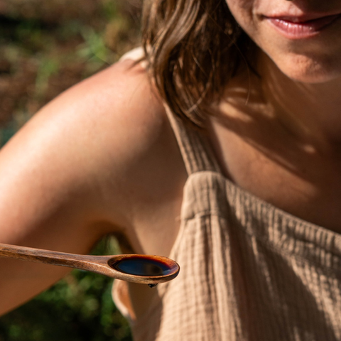Woman holding a wooden spoon of dark purple liquid